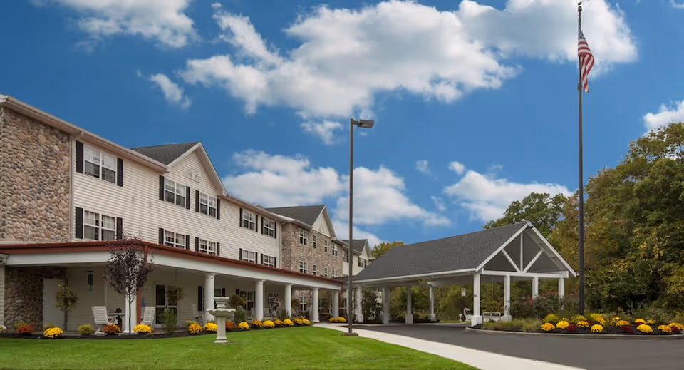 Exterior view of Voorhees Senior Living building with entrance canopy and flagpole.