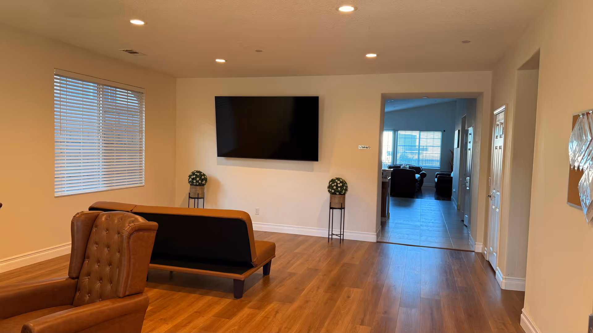 A spacious living area with a wall mounted TV and leather seating.