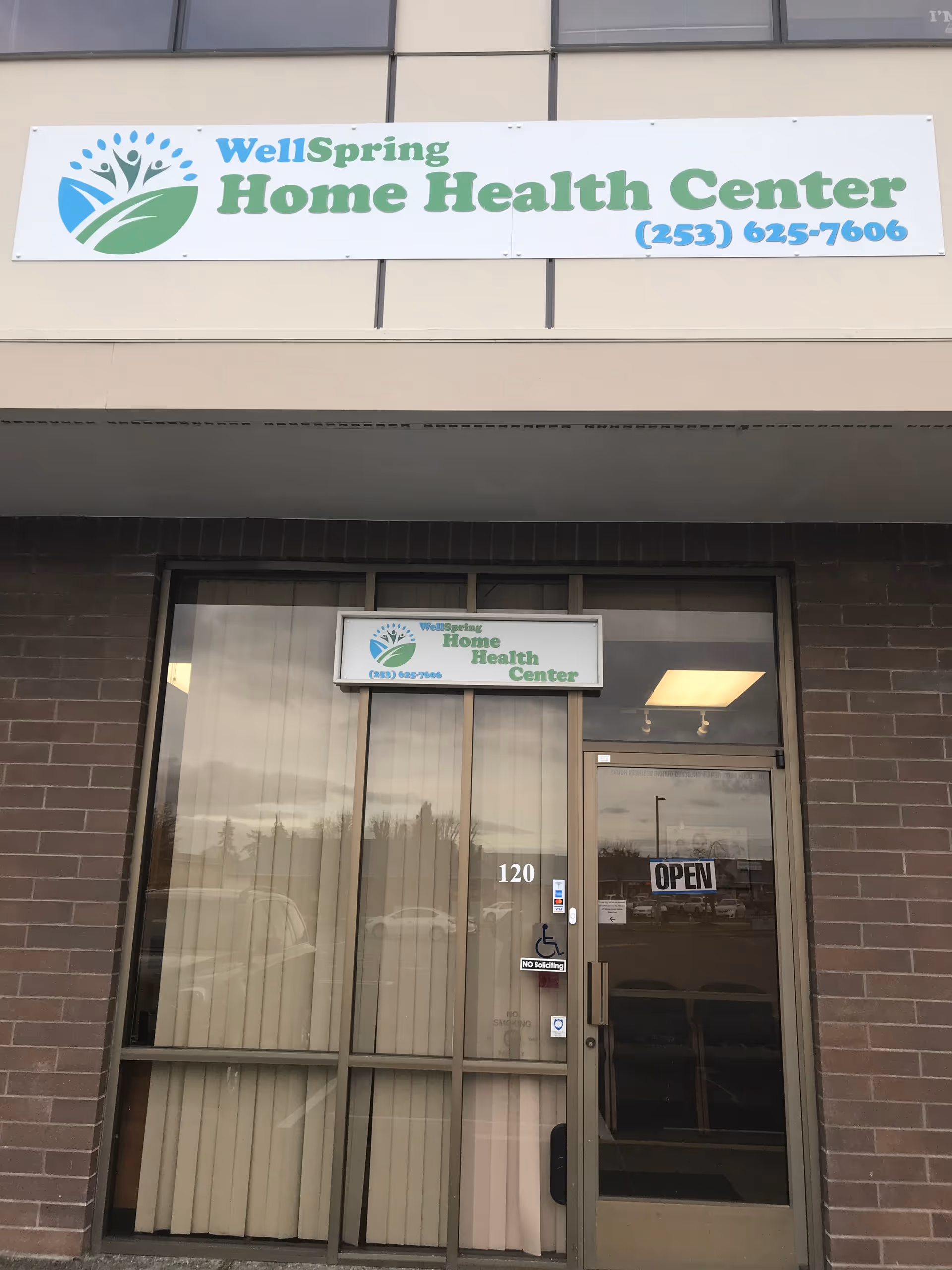 Exterior view of Wellspring Home Health Center entrance with sign and open door.