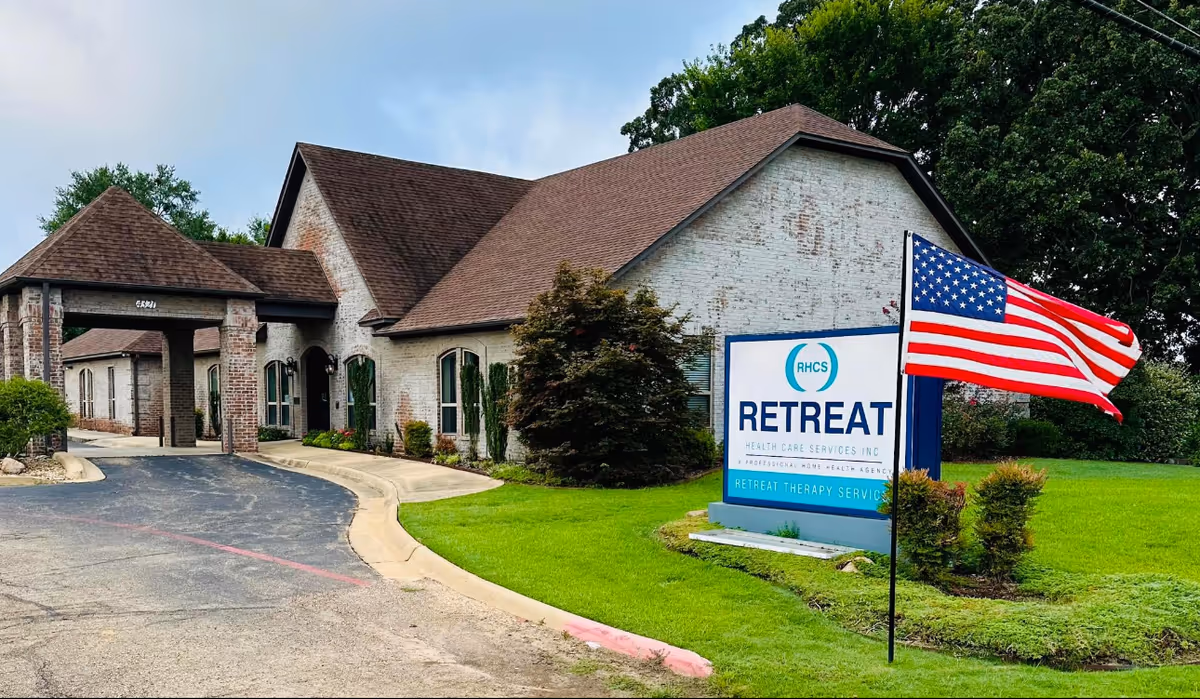 Exterior view of Retreat Healthcare Services facility with a sign and American flag.