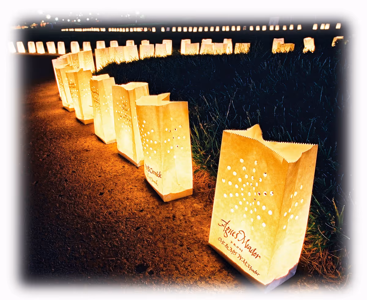 Row of glowing paper lanterns along a dark outdoor path at night