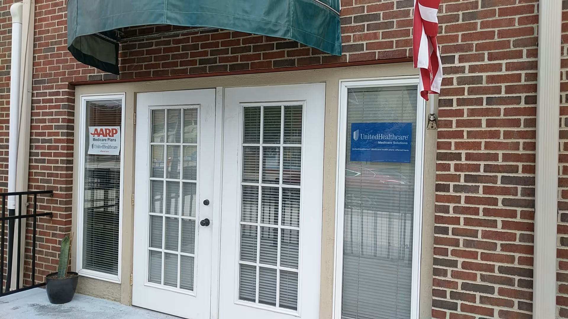 Brick exterior entrance for Heritage Home Health Care & AG with French doors and green awning.