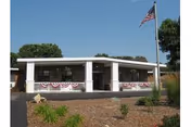 Front exterior view of a single-story facility with flagpole and patriotic bunting.