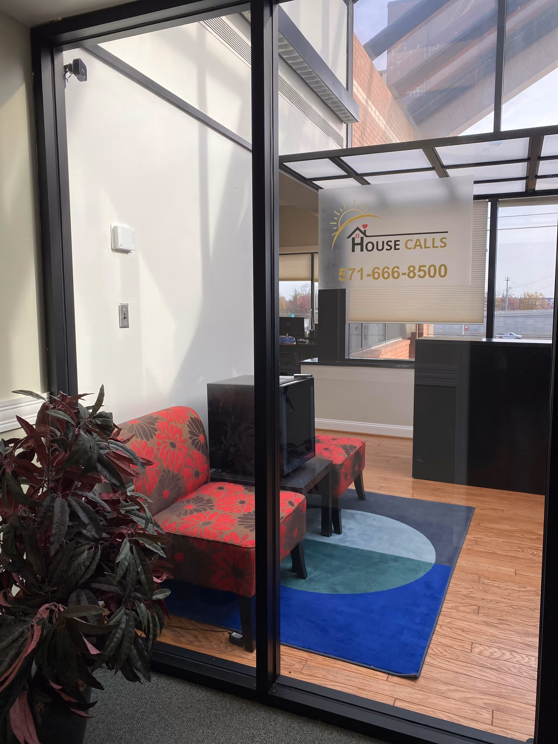 Glass-walled reception area with red patterned chairs, plant, and a House Calls lobby sign.
