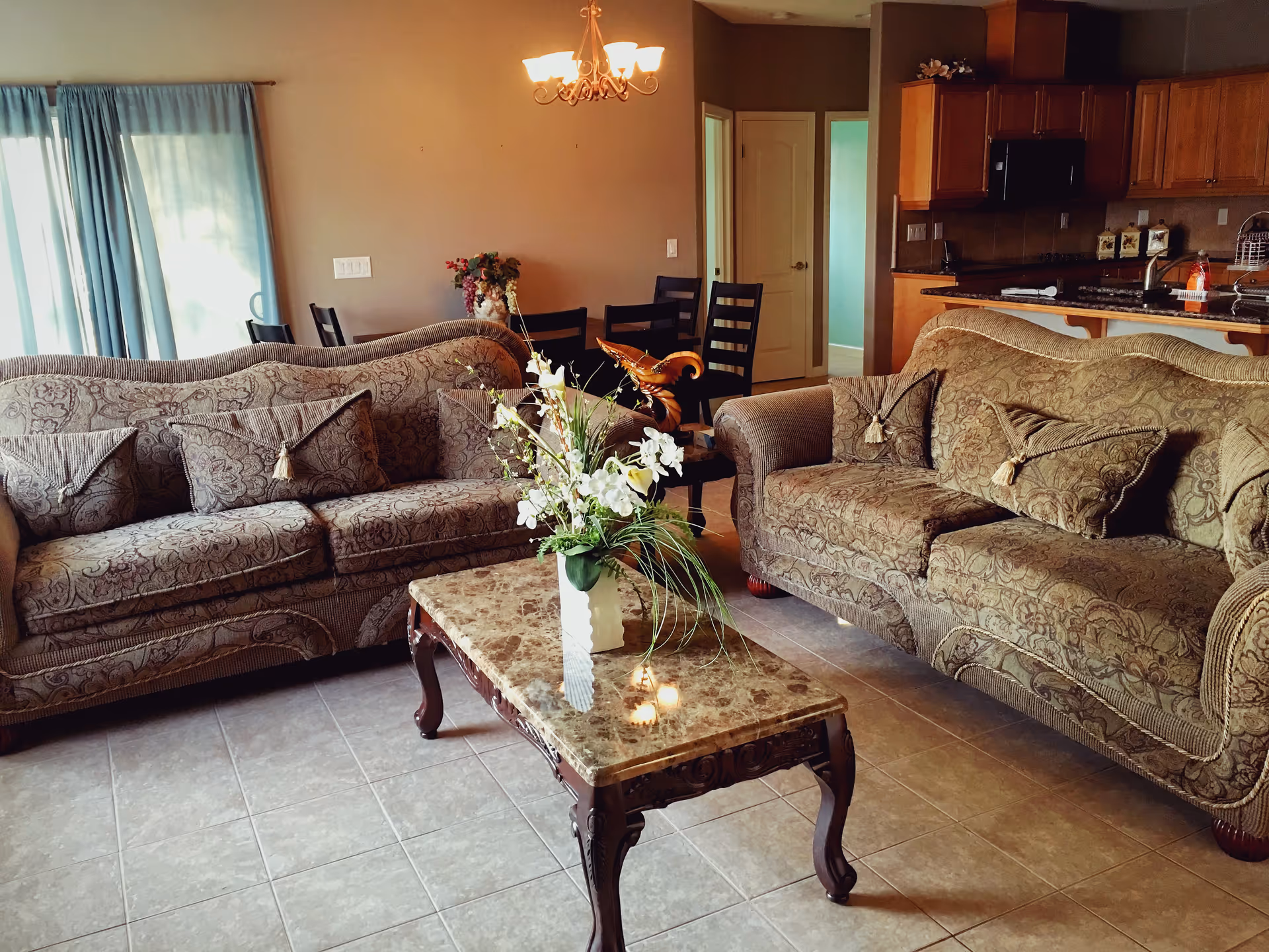 Two patterned sofas surround a marble coffee table in a spacious living room.