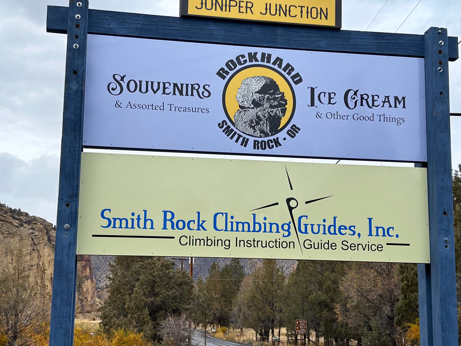 Outdoor signboard advertising souvenirs and climbing guides with mountainous backdrop.