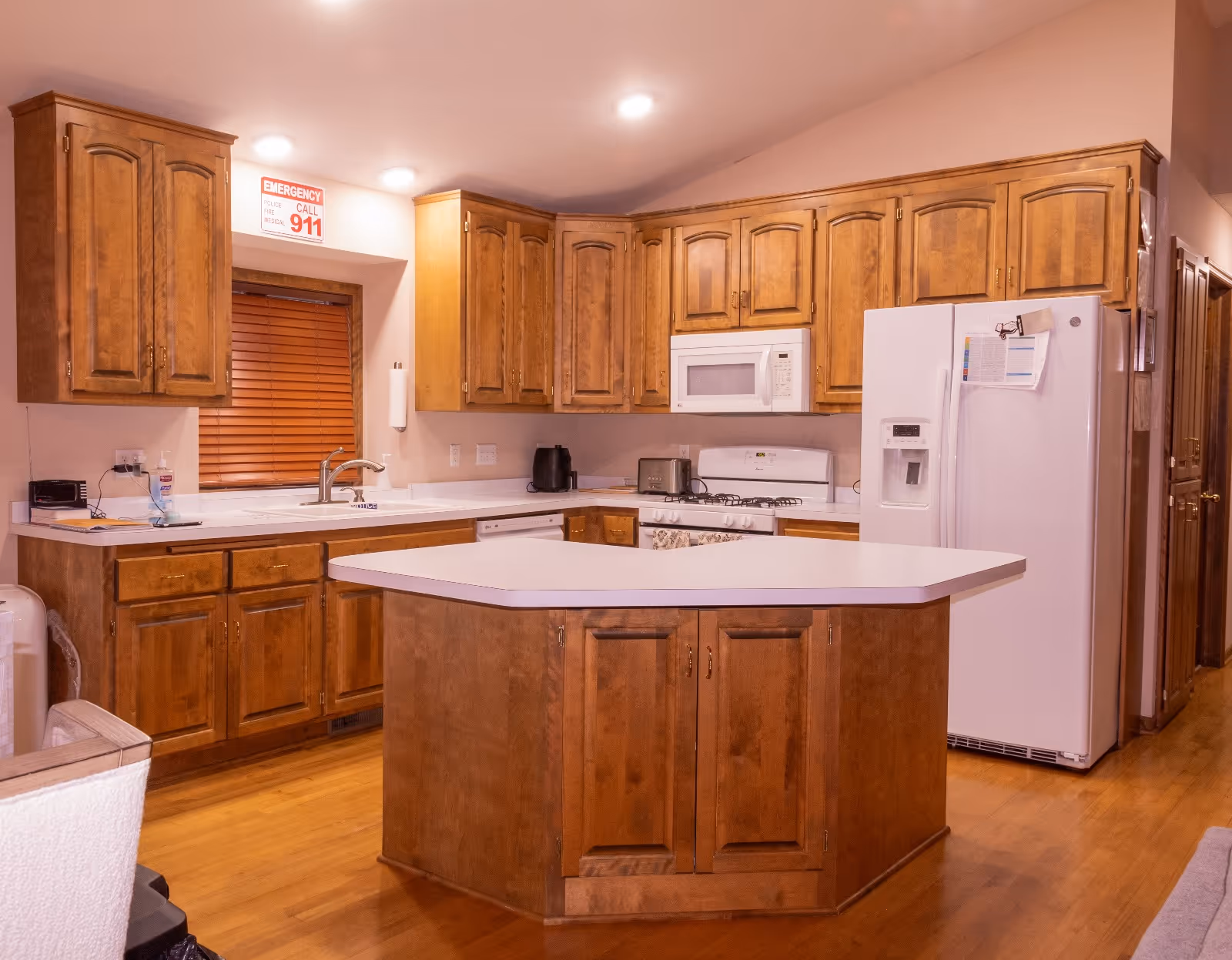 A spacious wooden kitchen with island, cabinets, and appliances in a senior living facility.