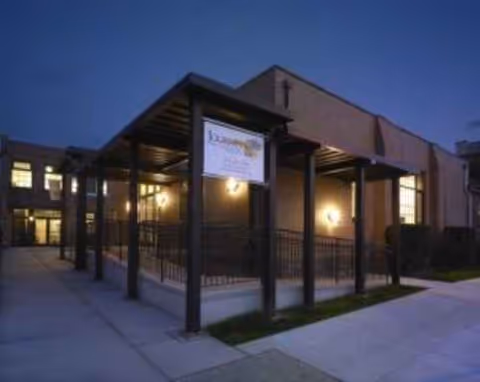 Exterior view of a brick adult day center with a covered walkway and sign.