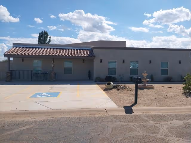 Exterior view of a single-story care center with accessible parking and desert landscaping.