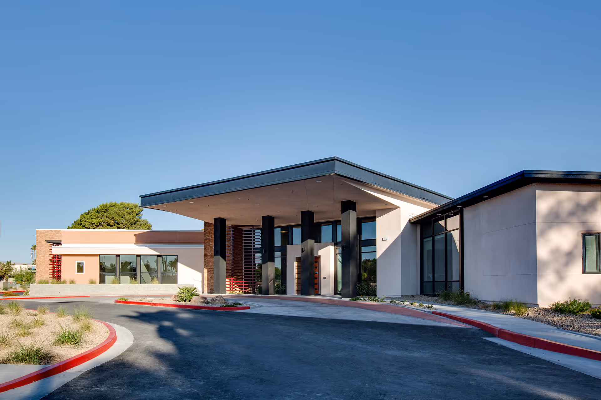 Modern senior living facility entrance with a covered driveway and glass doors.