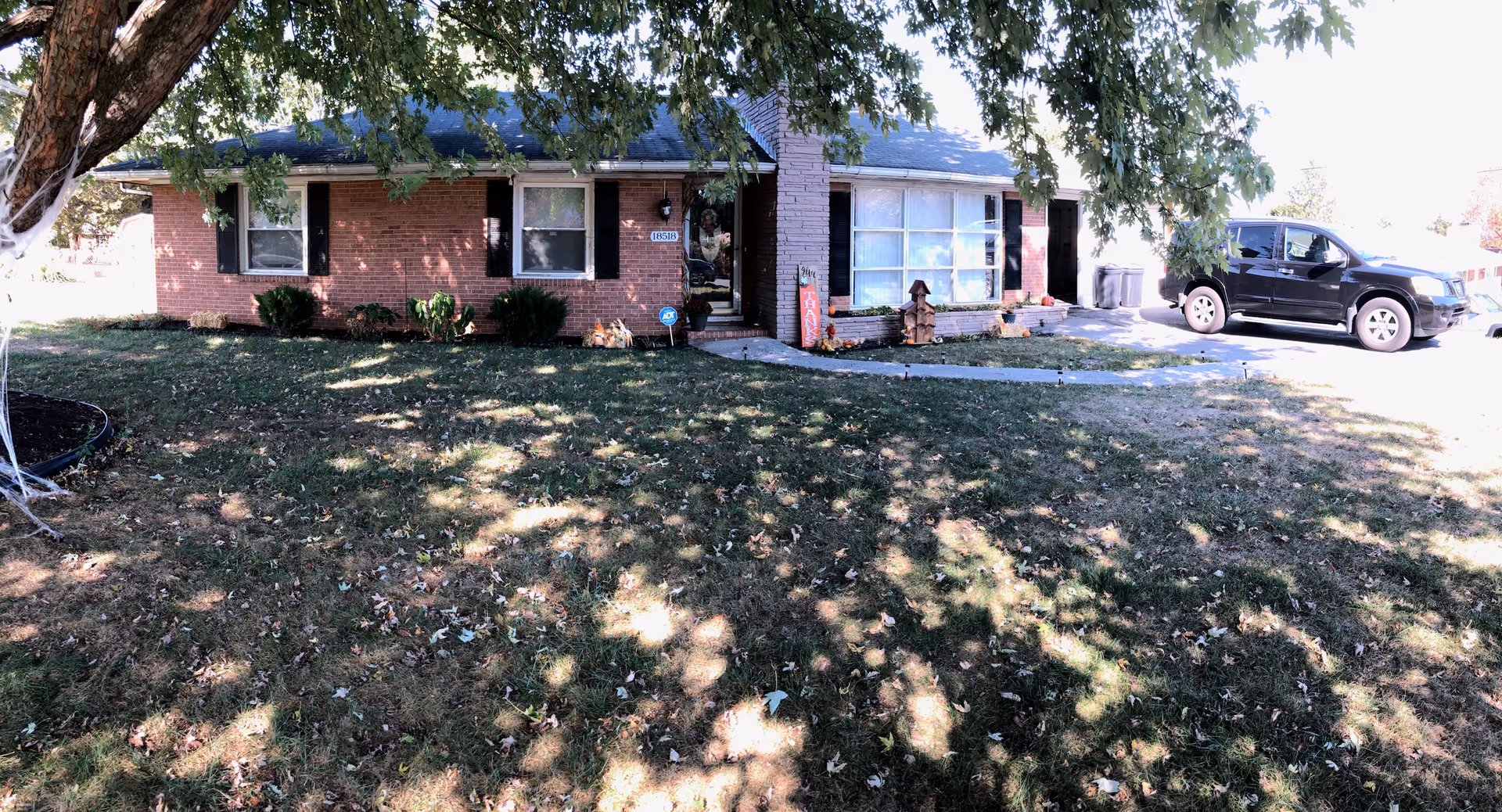 Brick single-story facility with front yard, tree shade, and a black SUV parked outside.