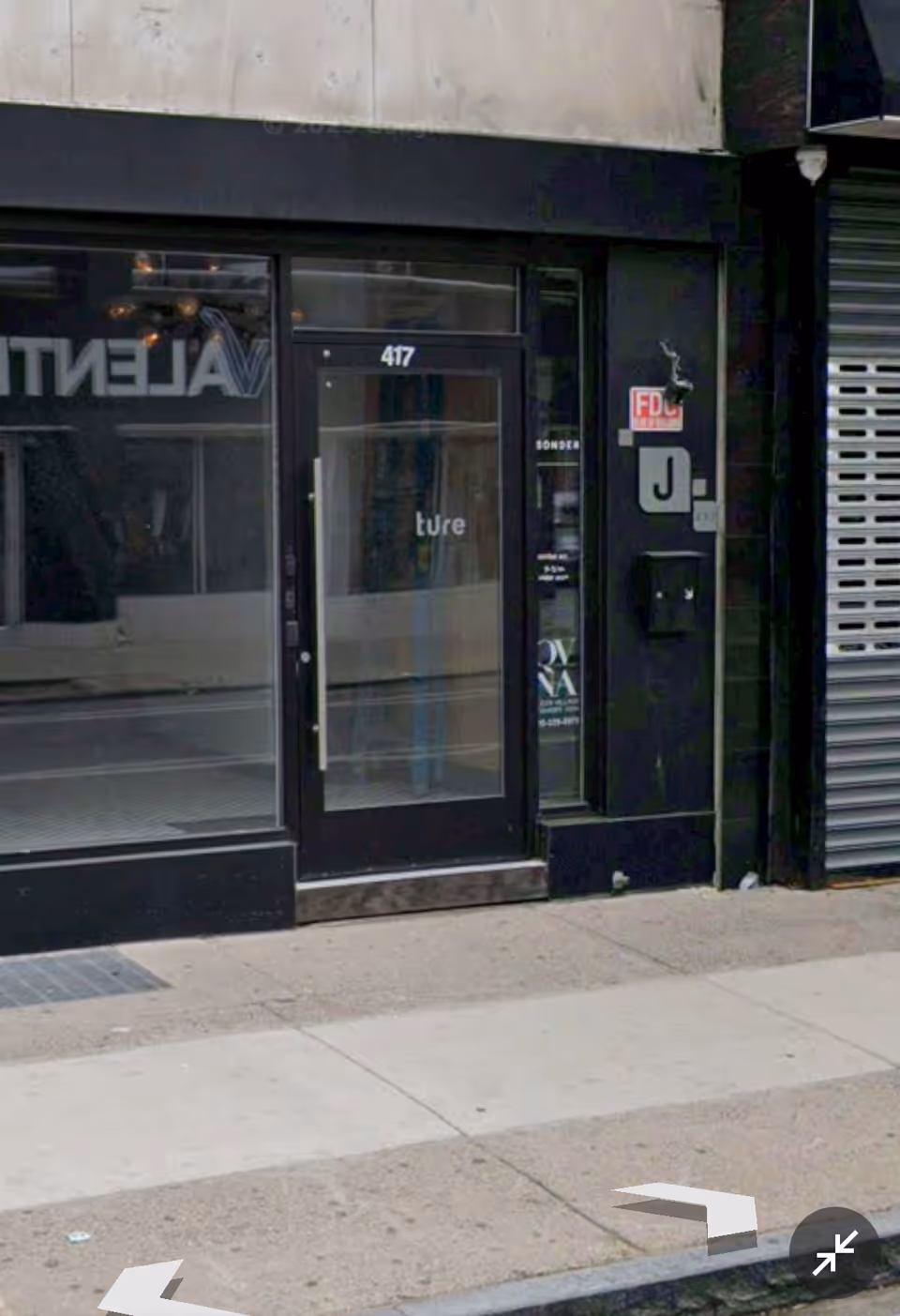 Storefront entrance with glass door on a city sidewalk.