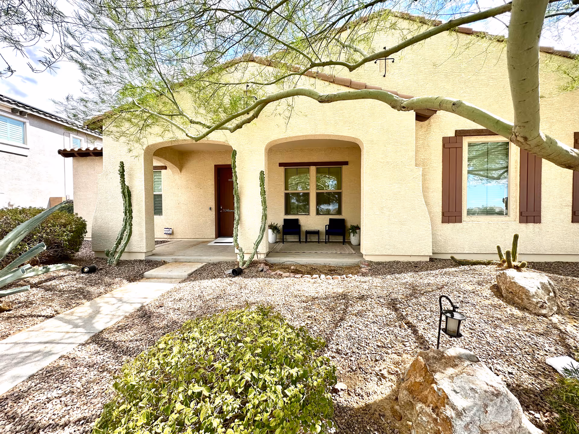 Beige senior living facility exterior with arched porch and desert landscaping.