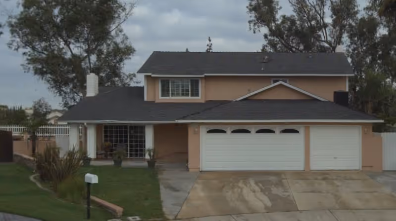 Two-story peach-colored house with a three-car garage and front yard.