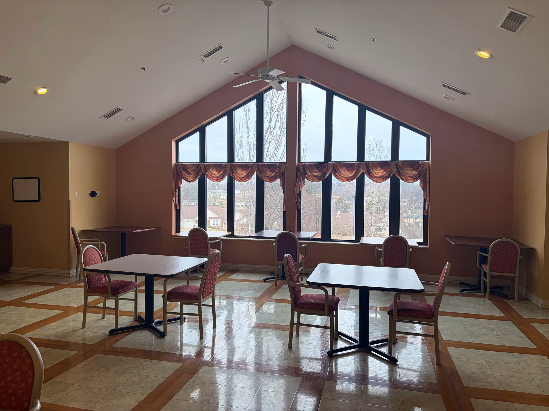 Bright, spacious dining area with large arched windows and red cushioned tables.