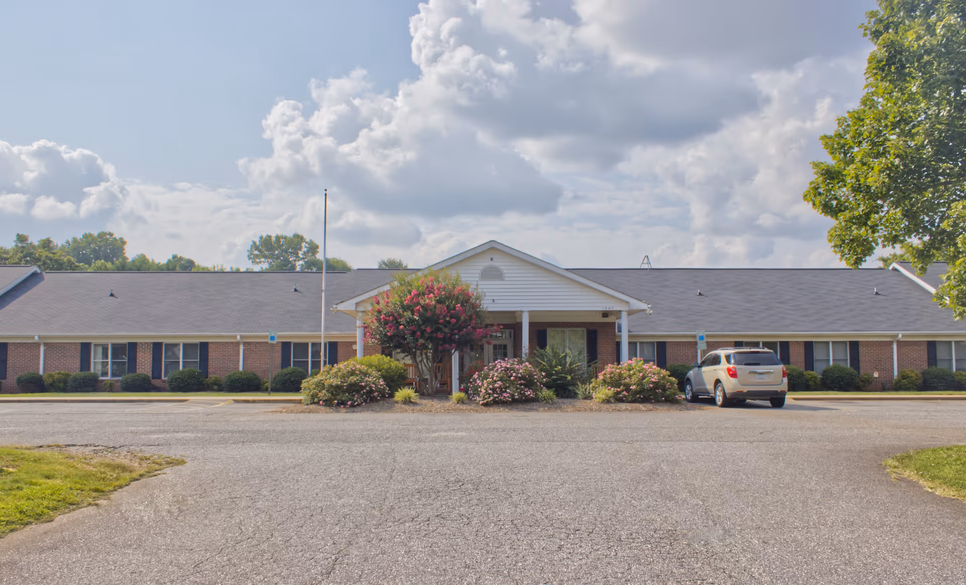 Front view of Jurney's of Statesville showing the entrance with flowering bushes and a parked car.