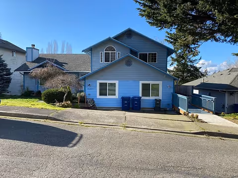 Blue two-story house-style facility with blue bins out front.