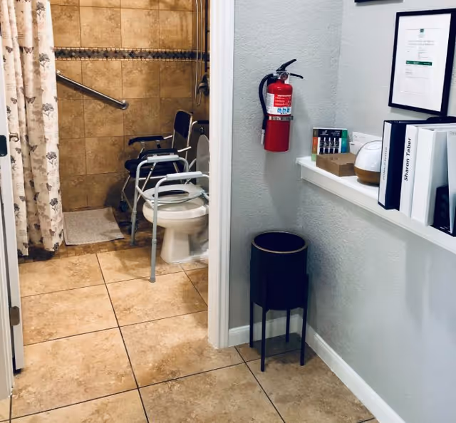 Accessible bathroom with toilet, shower, and mobility aids in a senior living facility.