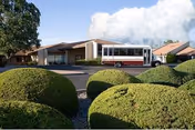 Front view of a care center with a bus parked beside manicured shrubs.