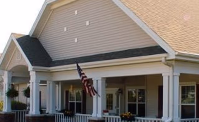 Front entrance of Brookdale Niagara senior living facility with porch, columns, and flag.