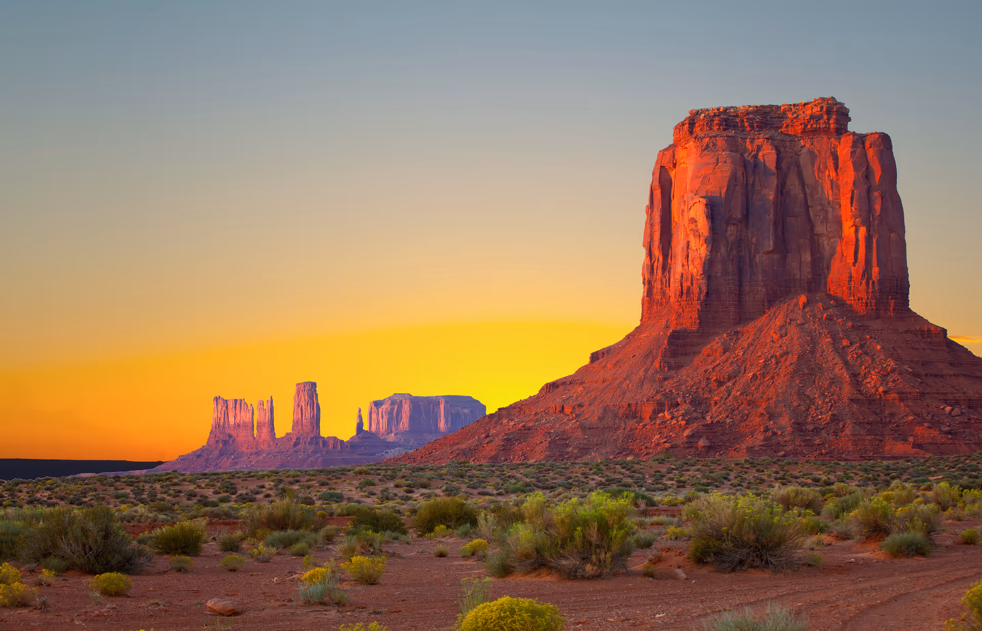 Desert landscape at sunset in Arizona with large red rock formations and sparse vegetation.