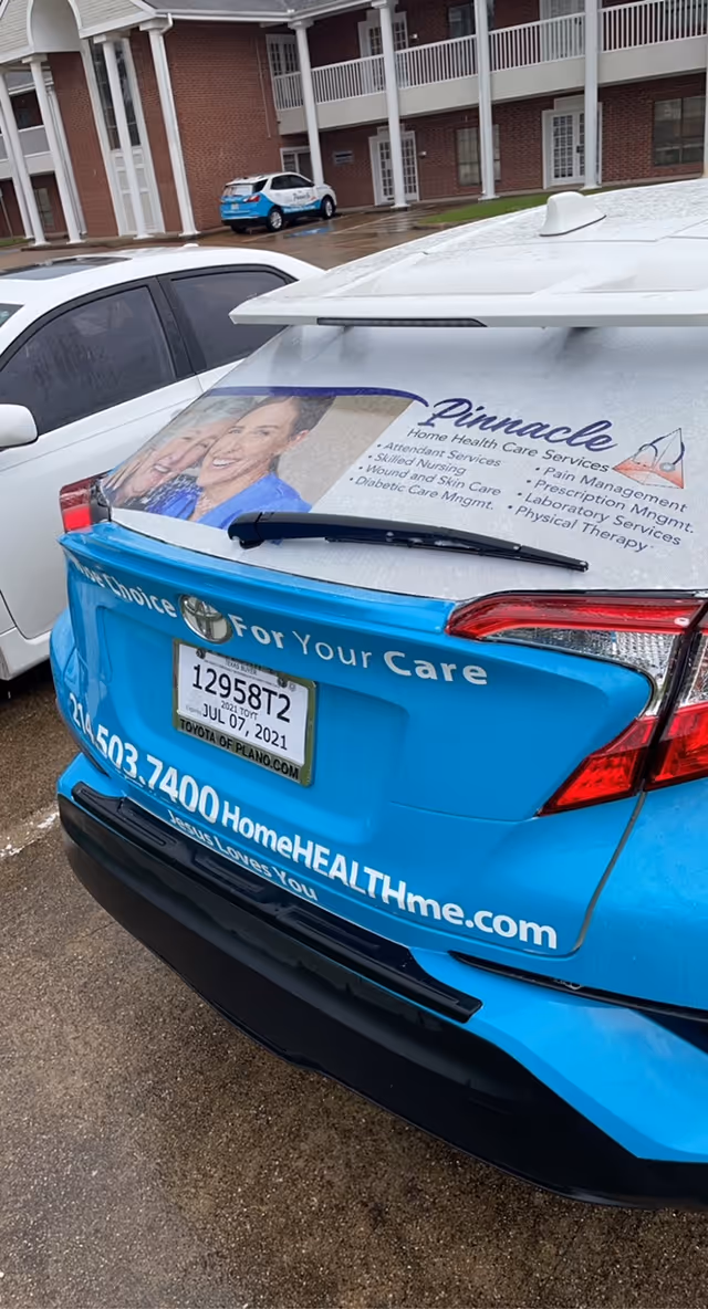 Rear view of a blue Pinnacle Home Health Care Services vehicle parked outside a brick facility.