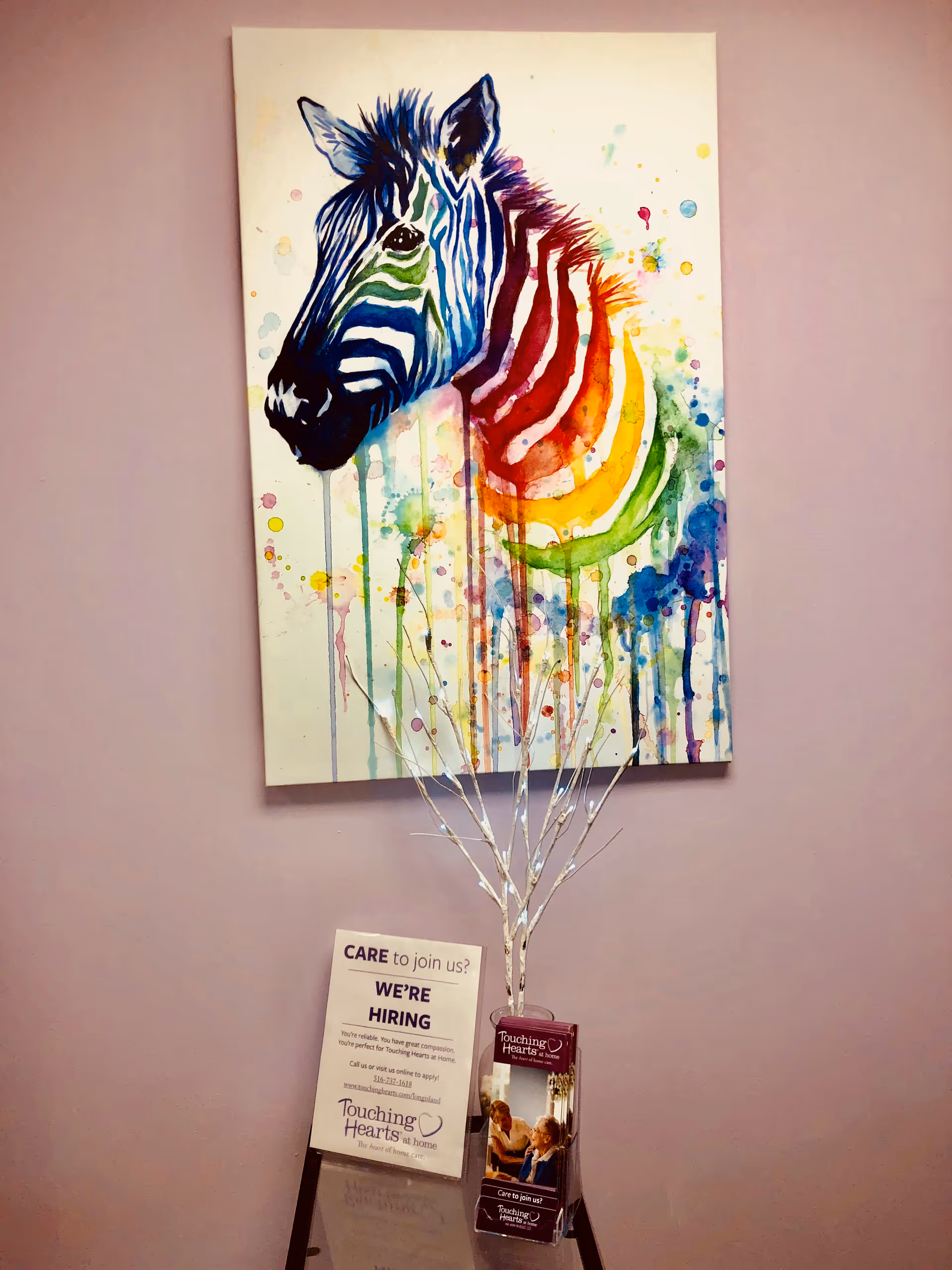 Colorful zebra painting on a pink wall with hiring sign and brochures.