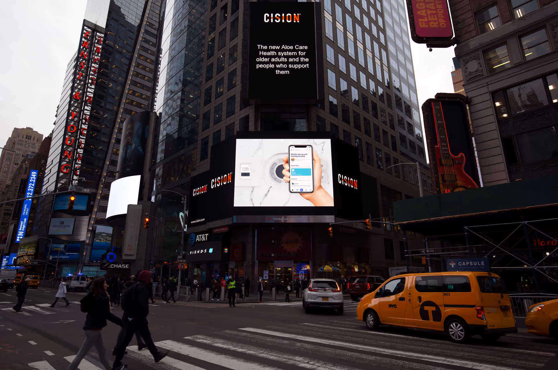 Busy urban intersection with pedestrians, taxis, and towering digital billboards.