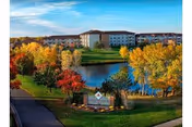 Aerial view of Gem's Senior Living I campus with autumn trees, pond, and surrounding buildings.