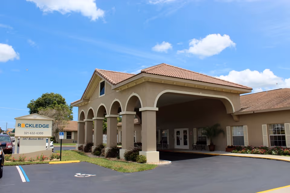 Front entrance of Rockledge Health & Rehabilitation Center showing an arched porte-cochere and a sign by the driveway.
