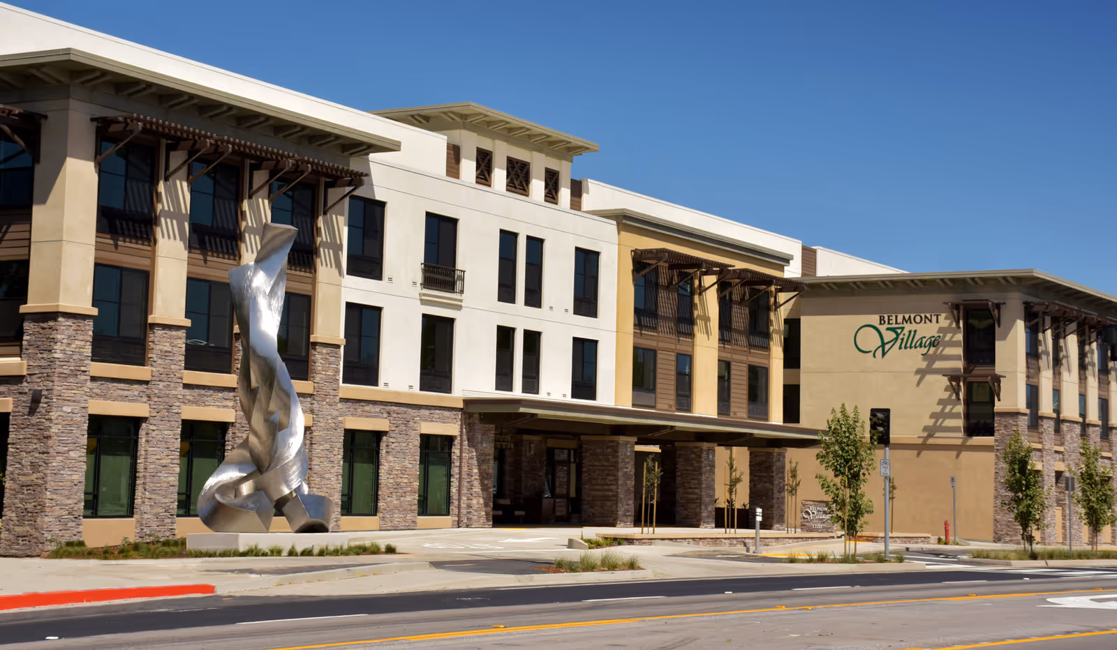 Exterior view of Belmont Village Senior Living Albany, showing the modern facility and sculpture.