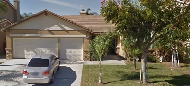 Eastvale Meadows facility exterior with a two-car garage, driveway, and small front yard.