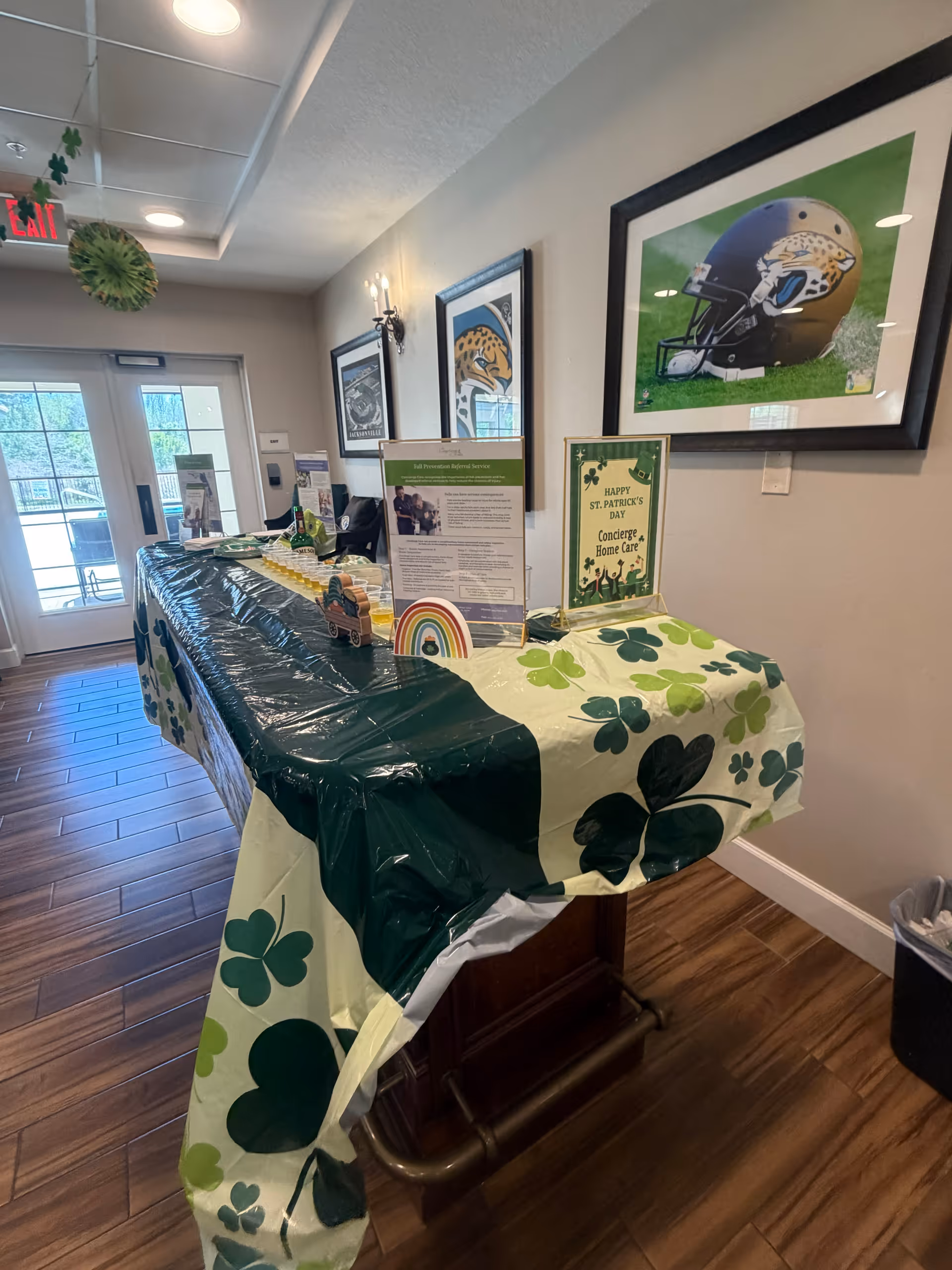 Interior hallway with a shamrock-themed display table and framed sports pictures.