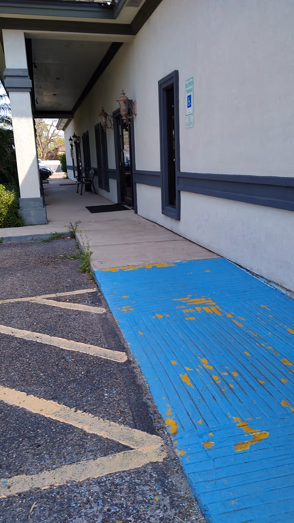 Exterior corridor beside Palm Valley Health Care II, Inc building with a blue ramp.