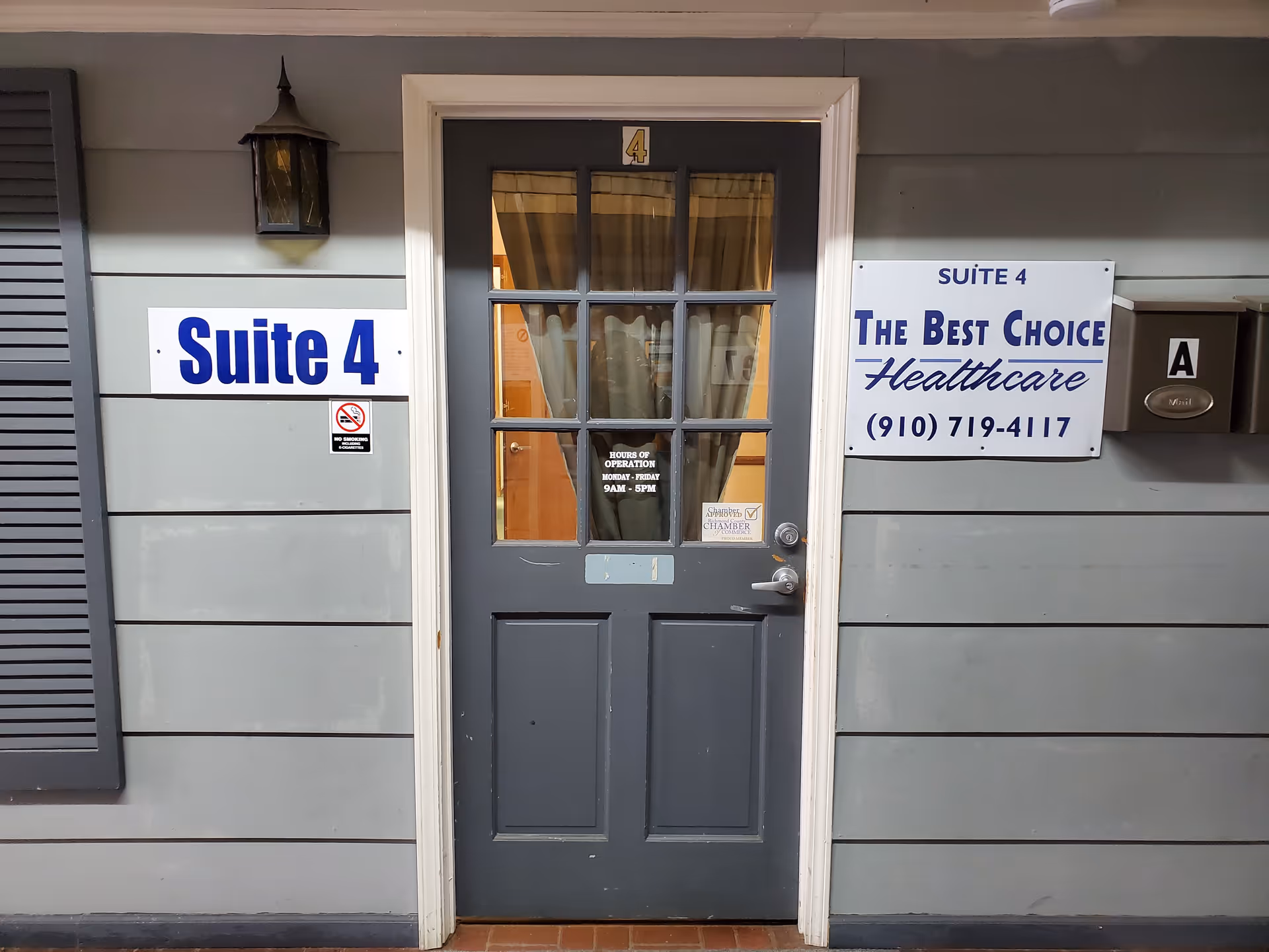 Gray exterior wall featuring a dark door labeled Suite 4 and healthcare signs.