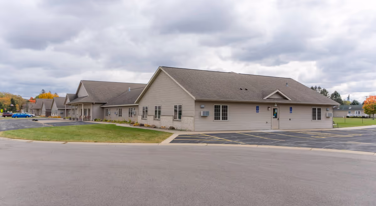 Single-story beige senior living facility with a parking lot and grassy front lawn