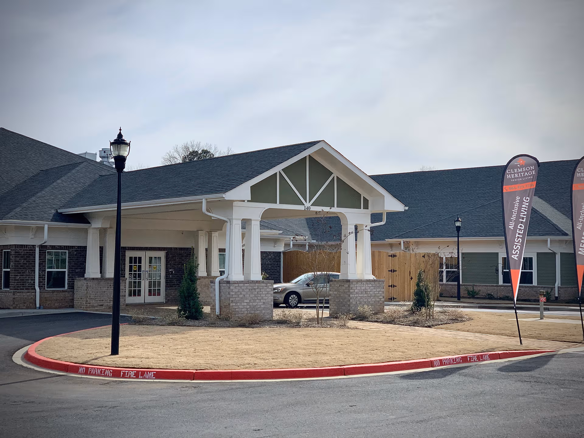 Exterior view of Clemson Heritage Senior Living entrance with porte-cochère and flags.