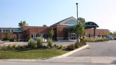 Exterior view of a brick medical center with glass entrance and parking.