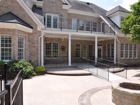 Brick-faced assisted living building entrance with a covered porch, columns, accessibility ramp and second-story balcony.