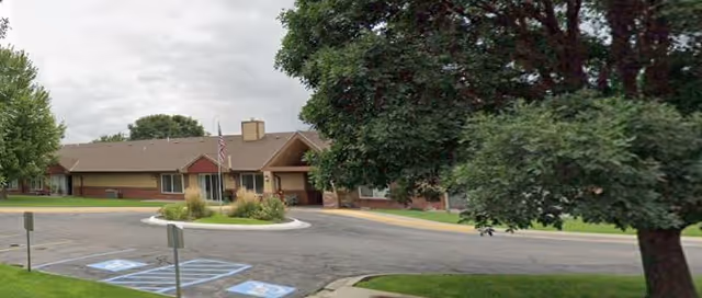 Exterior view of Regency Retirement Residence with entrance, parking, and trees.