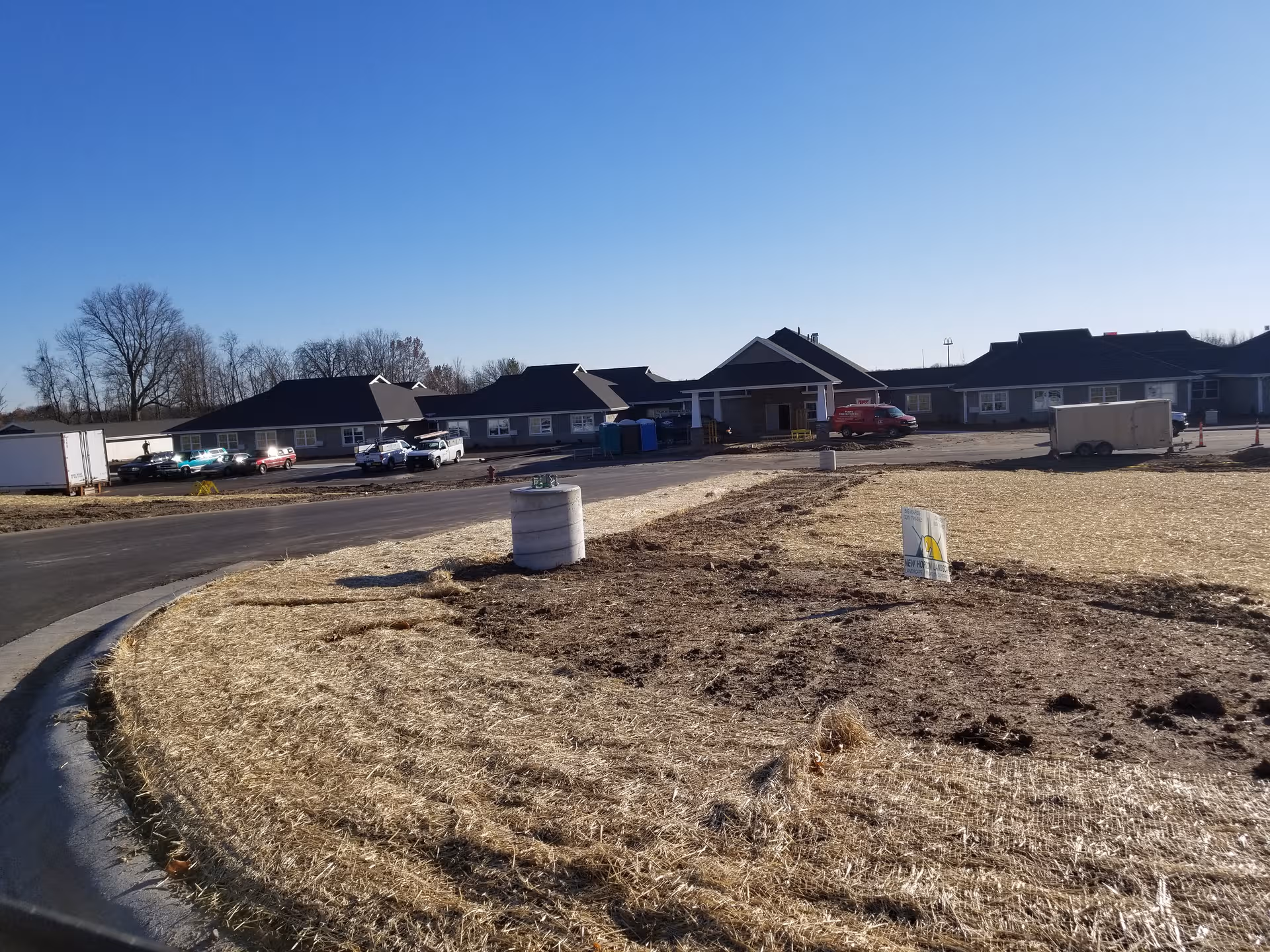 Senior living facility exterior under construction with front entrance and parked cars
