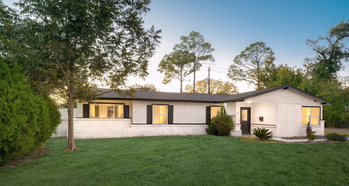 One-story white brick assisted living building with windows and a neatly mowed green lawn.