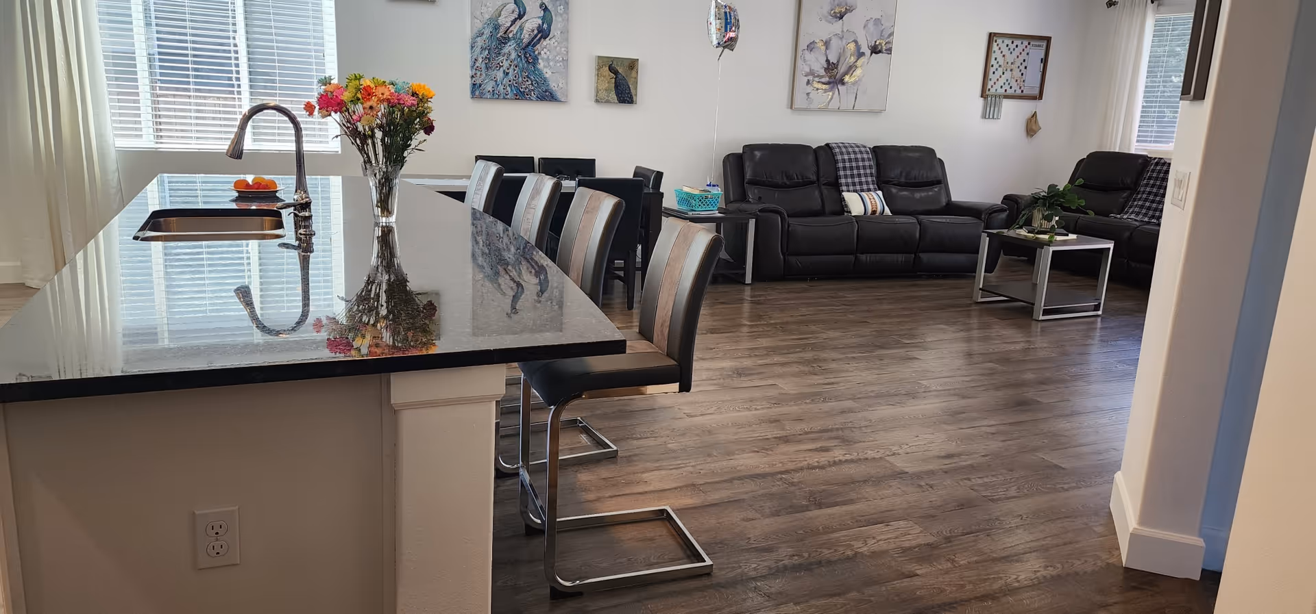 Open-concept common area with a kitchen island, stools, and black leather seating