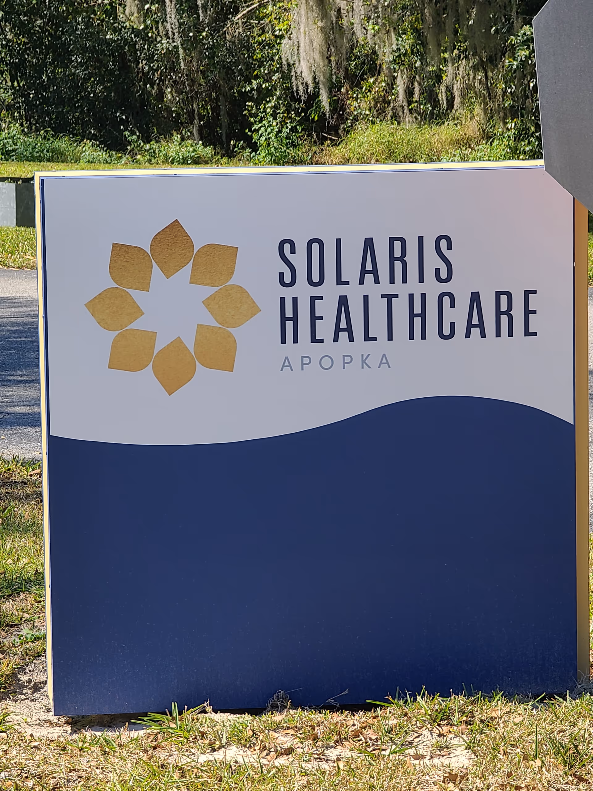 Outdoor sign for Solaris Healthcare Apopka with a gold geometric flower logo.