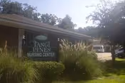 Exterior view of a brick nursing center with a sign and landscaping.