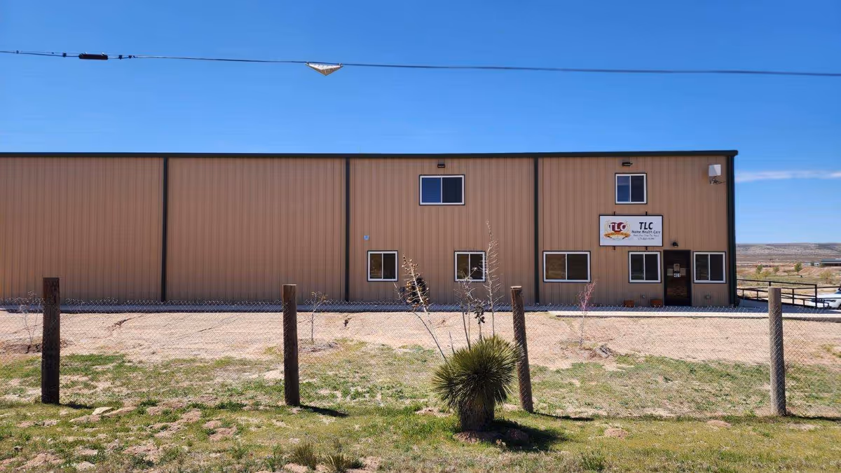 Exterior of a tan warehouse-style facility with TLC Home Health Care sign.