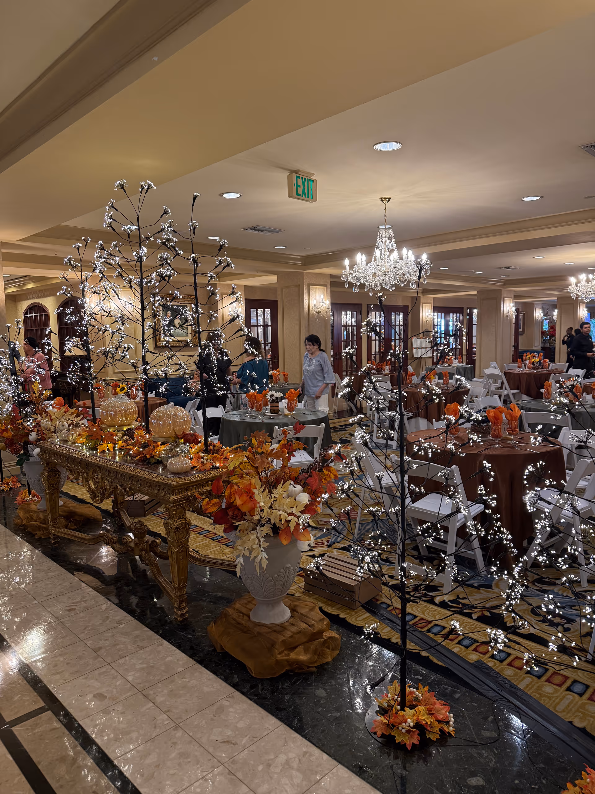 An upscale senior living dining hall with chandeliers, decorated tables, and floral centerpieces.