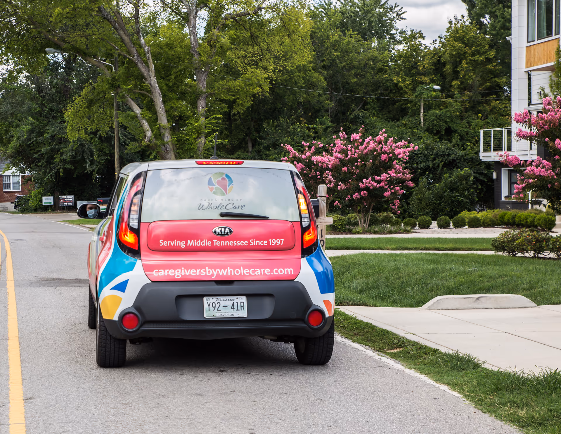 Rear view of a Caregivers by WholeCare van parked on a residential street.