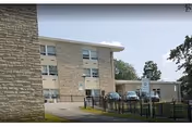 Exterior view of Highland Rehabilitation & Nursing Center with brick facade and parking lot.