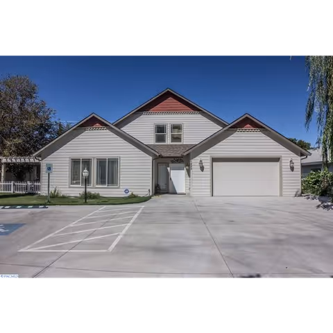 Single-story senior living facility exterior with three gables and a two-car garage.
